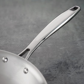 Ergonomic riveted handle on the Tramontina tri-ply fry pan for secure grip.