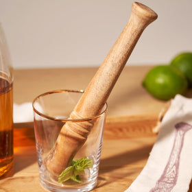 Twine wooden muddler resting in burlap pouch for storage and decor.