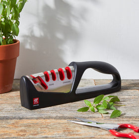 ZWILLING knife sharpener demonstrating coarse and fine ceramic slots for edge refinement